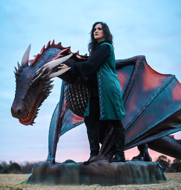 Woman in dark green dress and red and black skin robot animatronic dragon on lawn